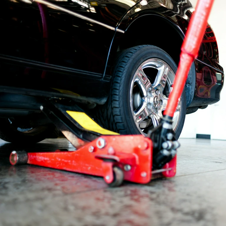 Czerwony podnośnik pneumatyczny pod czarnym samochodem